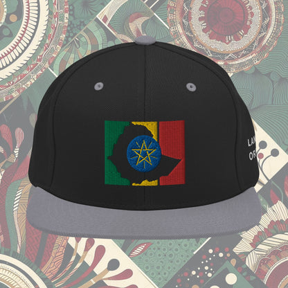 grey brim Ethiopia flag snapback from a Black-owned business with 'Land of Origin' on the side. Features vibrant flag colors. Perfect for showing national pride. Available now.